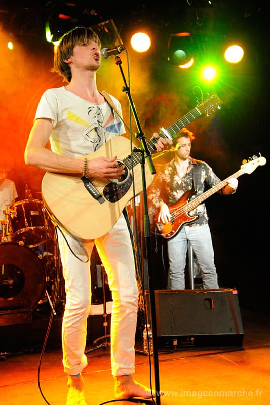 Chanteur guitariste de Hangar et bassiste sur scène en concert privé éclairé orange