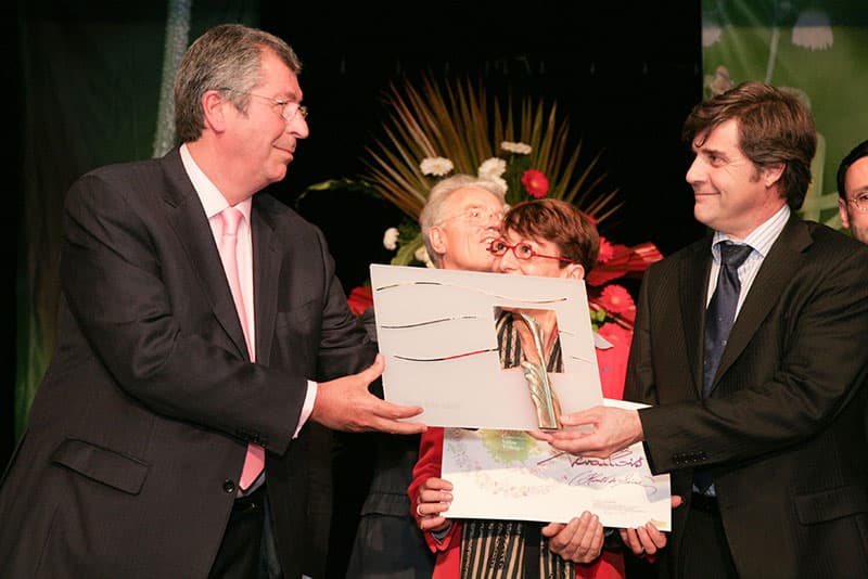Remise de diplôme et trophée entre deux hommes sur scène lors d'une cérémonie